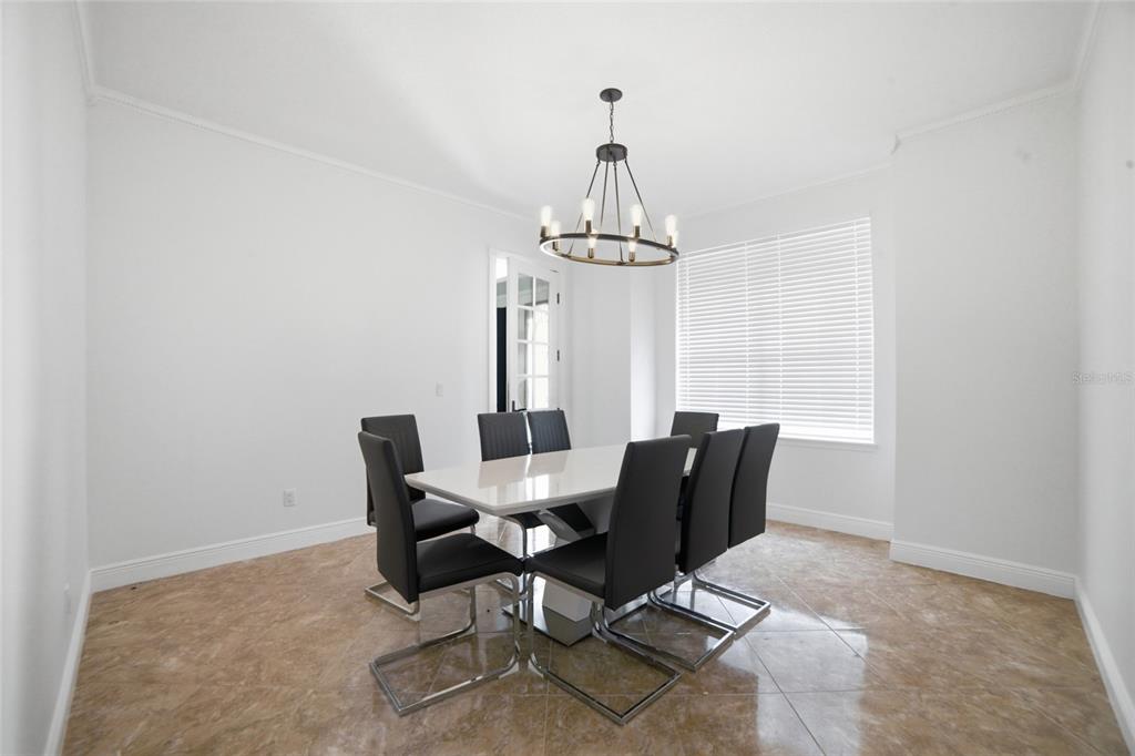 A dining room features a white table, six black chairs, and a modern chandelier — 2054 PALM VISTA DRIVE, APOPKA, FL