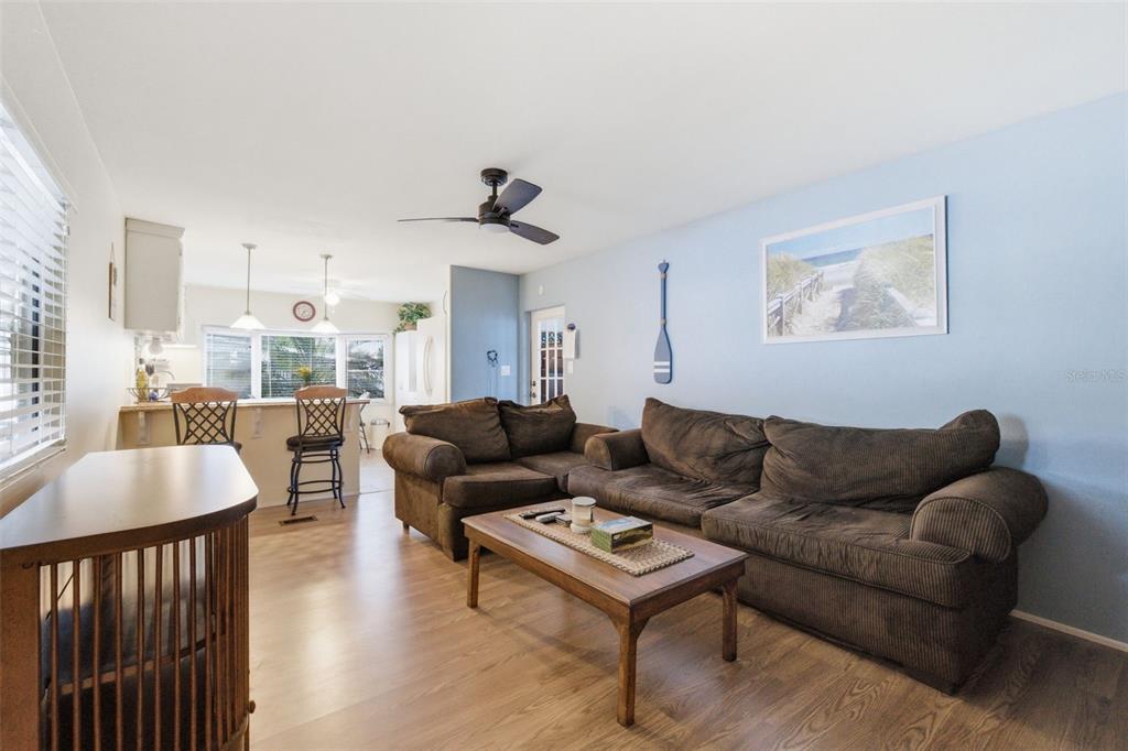 A living room features a brown sectional sofa, a wooden coffee table, and wood flooring — 6100 62ND AVENUE N UNIT 38, PINELLAS PARK, FL