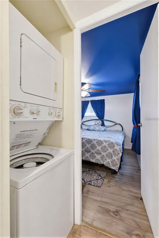 A stacked washer and dryer unit sits next to a bedroom with a blue ceiling — 6100 62ND AVENUE N UNIT 38, PINELLAS PARK, FL
