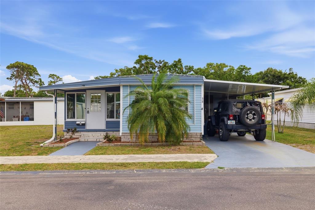 A blue mobile home with a carport and a Jeep parked in the driveway — 6100 62ND AVENUE N UNIT 38, PINELLAS PARK, FL