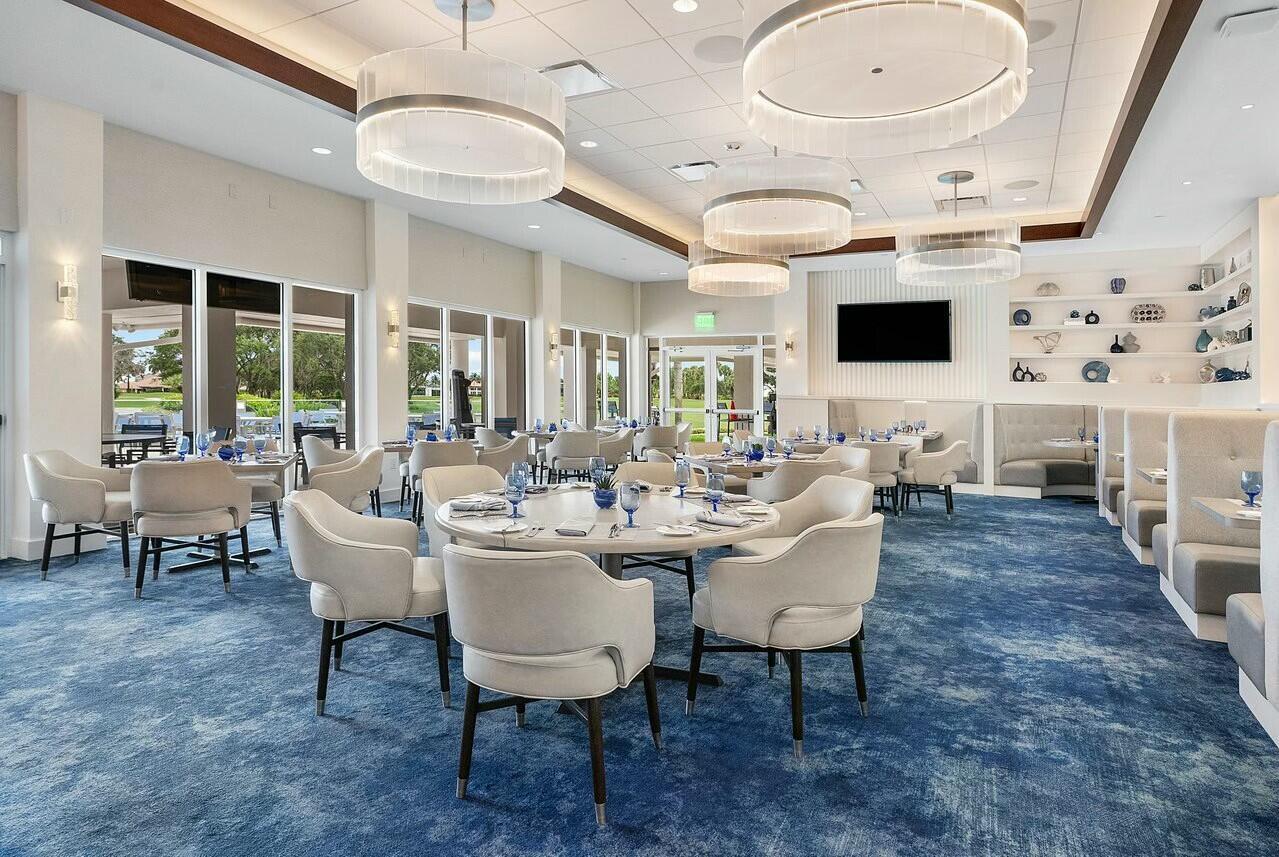 A dining room features round tables, upholstered chairs, blue patterned carpet, and modern pendant lighting — 4356 Kasso Circle, Boca Raton FL 33487, BOCA RATON, FL