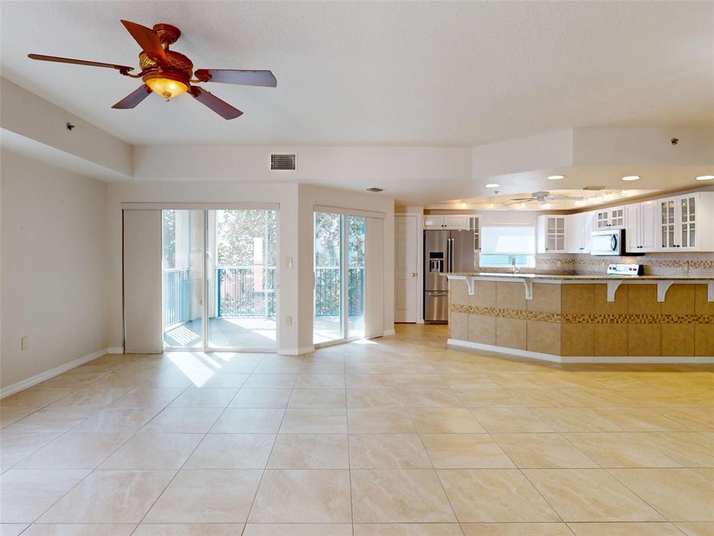 An open-concept living area with tile flooring, a kitchen island, and sliding glass balcony doors — 5300 S ATLANTIC AVENUE UNIT 9201, NEW SMYRNA BEACH, FL