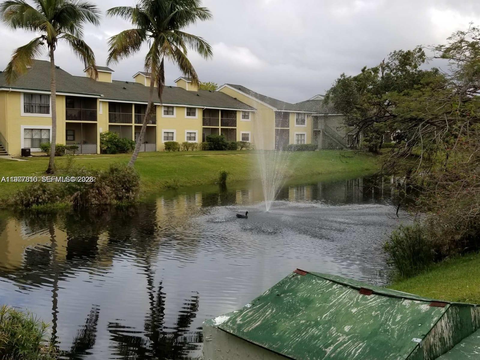 A pond with a fountain and a duck sits in front of a yellow apartment building — 3948 NW 87th Ave # 3948, Sunrise FL 33351, SUNRISE, FL