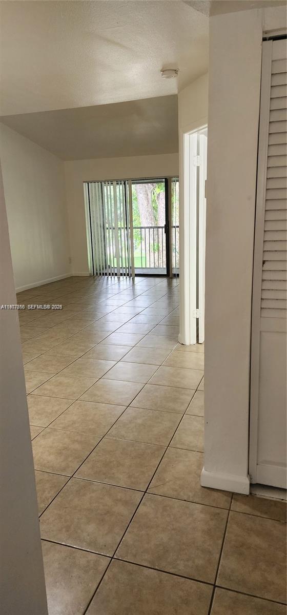 A room with beige tile flooring leads to a sliding glass door opening onto a balcony — 3948 NW 87th Ave # 3948, Sunrise FL 33351, SUNRISE, FL