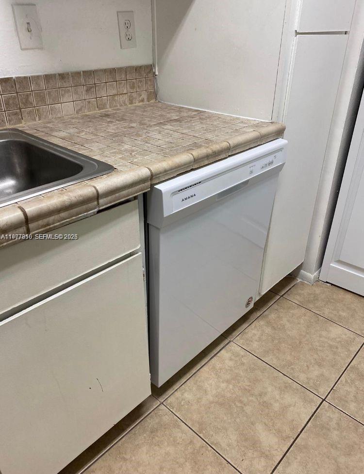 A white Amana dishwasher is installed under a tiled countertop next to a kitchen sink — 3948 NW 87th Ave # 3948, Sunrise FL 33351, SUNRISE, FL