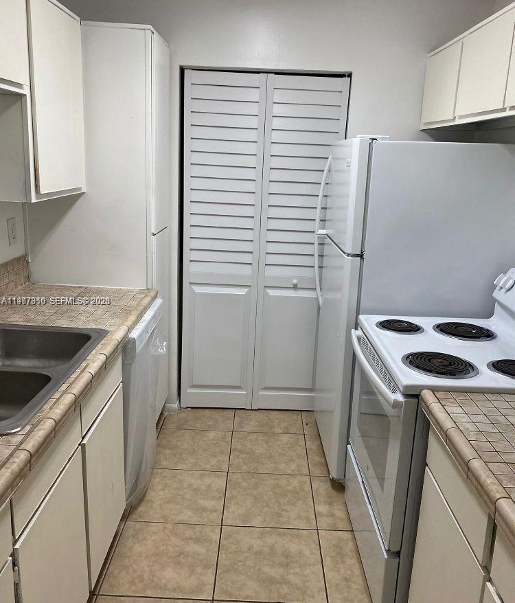 A galley-style kitchen features white cabinets, tiled countertops, and a white refrigerator — 3948 NW 87th Ave # 3948, Sunrise FL 33351, SUNRISE, FL