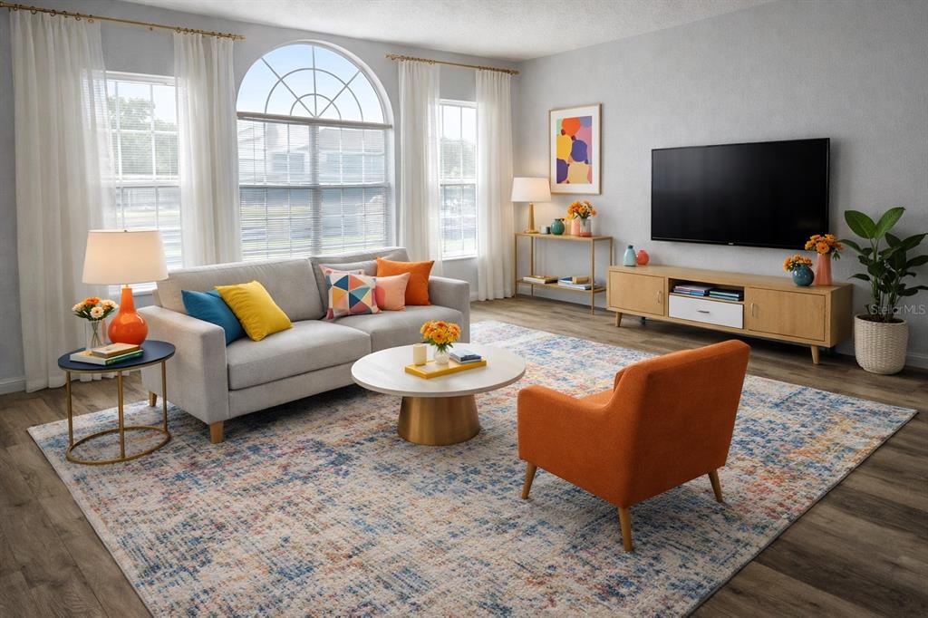 This is a digitally staged living room featuring a gray sofa, orange armchair, and television — 2494 SWEETWATER CLUB CIRCLE UNIT 52, KISSIMMEE, FL