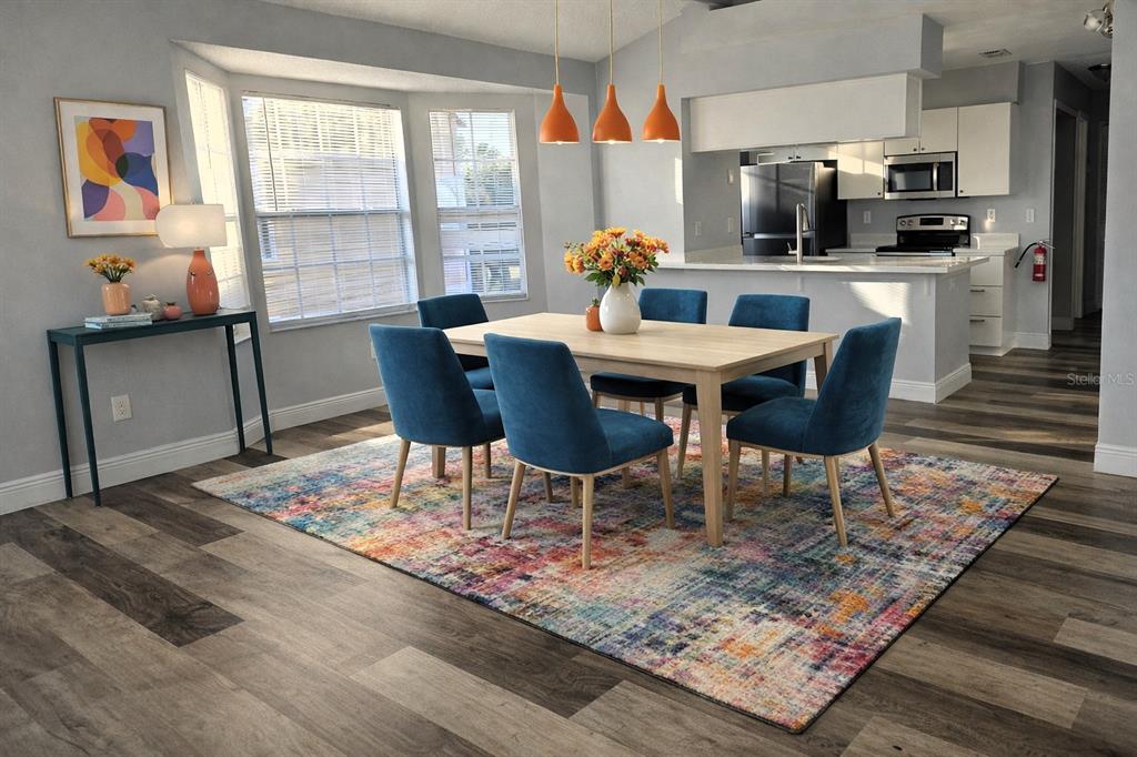 A dining area features a wooden table, blue chairs, and a colorful rug on wood-look flooring — 2494 SWEETWATER CLUB CIRCLE UNIT 52, KISSIMMEE, FL