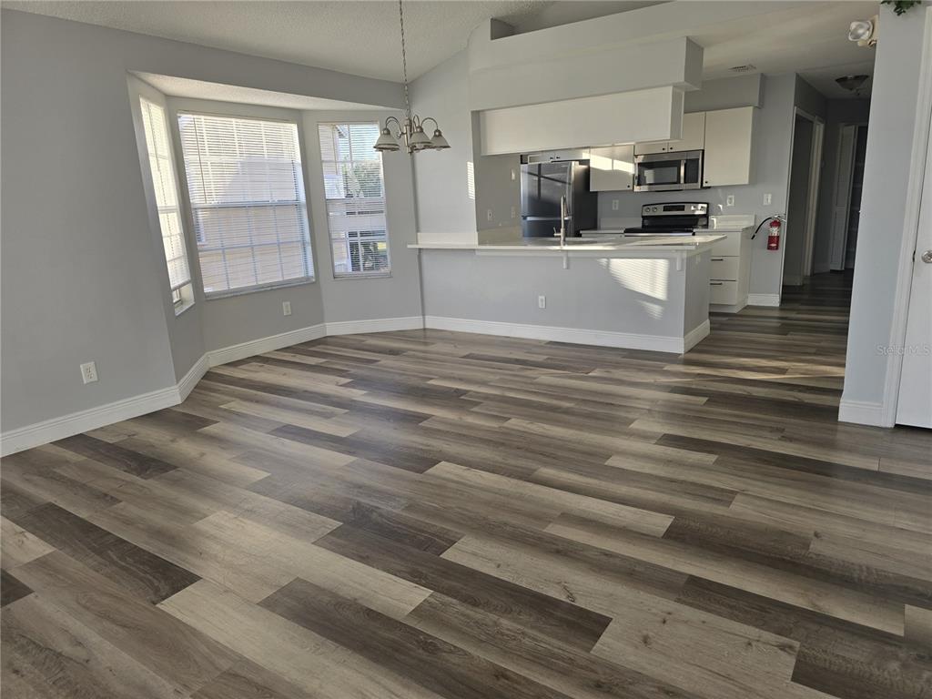 An open-concept dining area and kitchen feature light gray walls and wood-look plank flooring — 2494 SWEETWATER CLUB CIRCLE UNIT 52, KISSIMMEE, FL