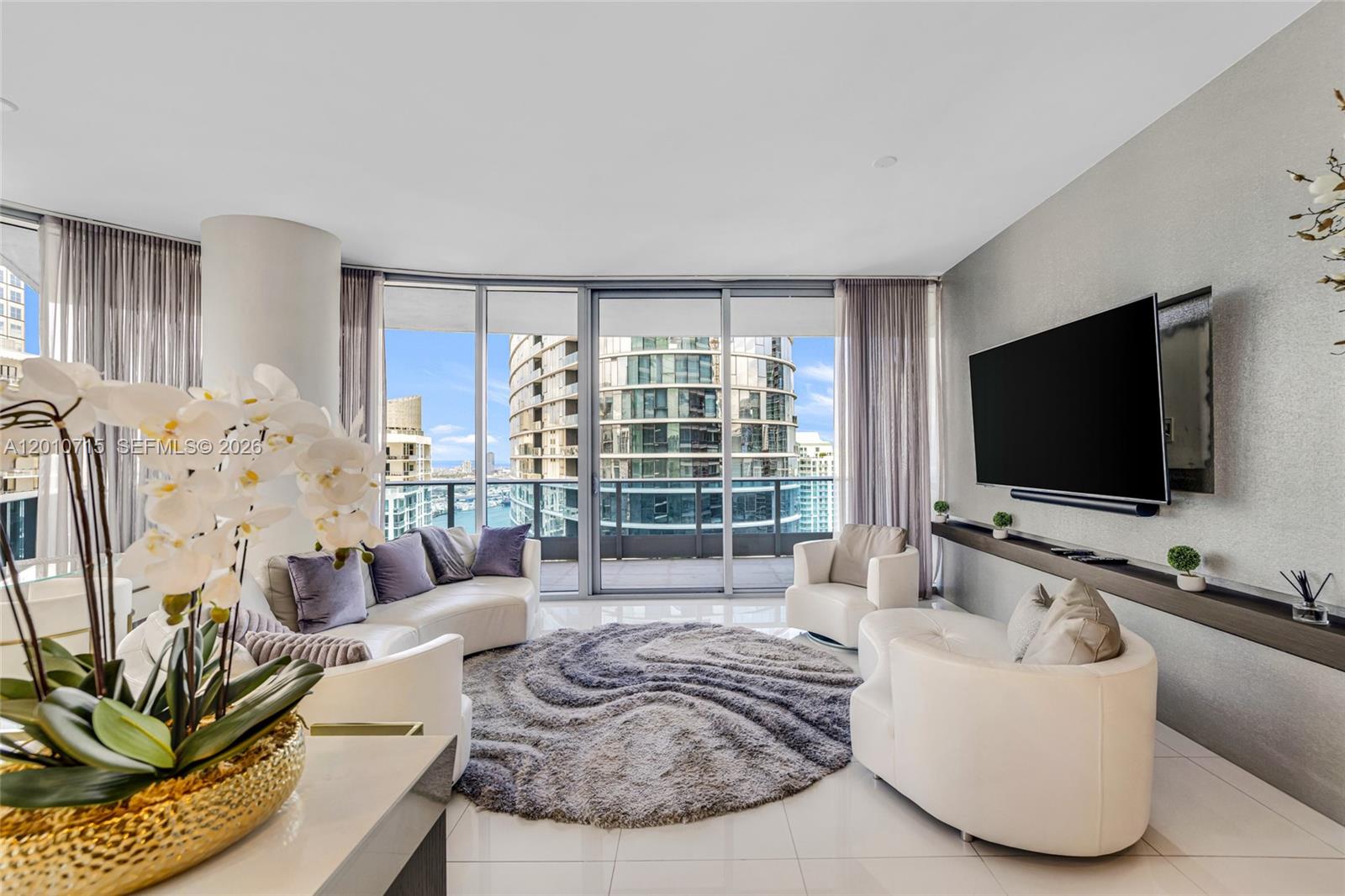 A modern open-concept living room and kitchen with floor-to-ceiling windows and white tile flooring — 200 Biscayne Boulevard Way # 4401, Miami FL 33131, MIAMI, FL