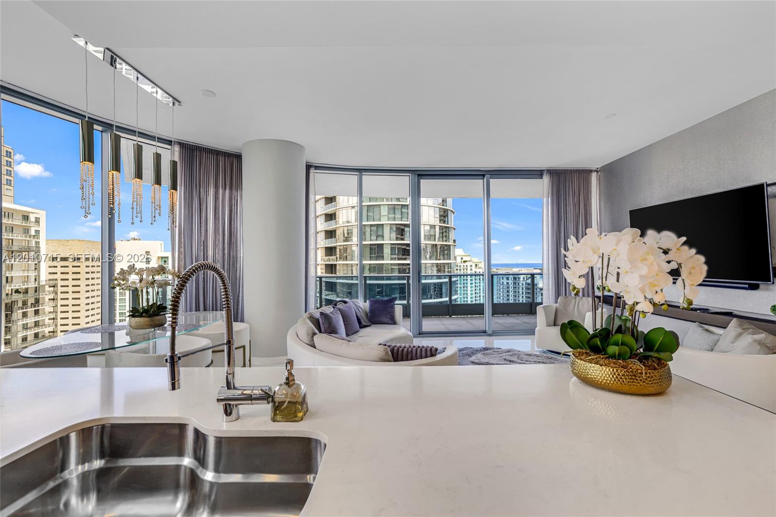 A modern kitchen island overlooks a living area with floor-to-ceiling windows and city views — 200 Biscayne Boulevard Way # 4401, Miami FL 33131, MIAMI, FL
