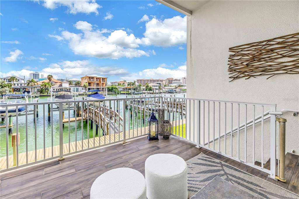 A balcony with wood-look tile flooring overlooks a canal with boat docks and houses — 161 BRIGHTWATER DRIVE UNIT 6, CLEARWATER BEACH, FL