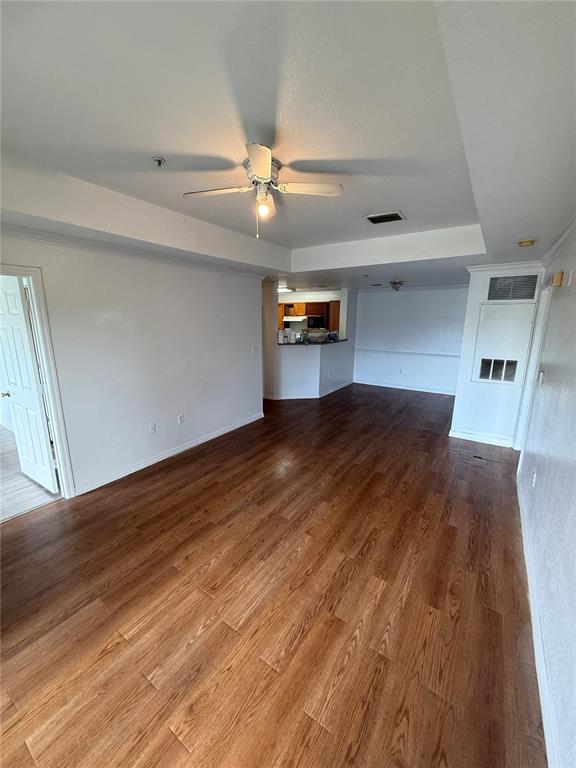 An interior view shows a living area with wood-look flooring, a ceiling fan, and a kitchen — 3712 CASTLE PINES LANE UNIT 4137, ORLANDO, FL