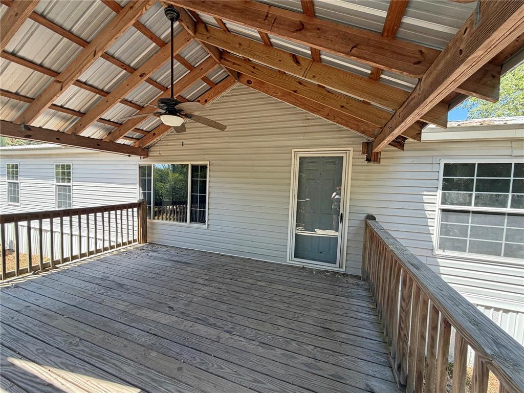 A covered wooden deck features a ceiling fan and railings attached to a house exterior — 120 PEACH, HAWTHORNE, FL