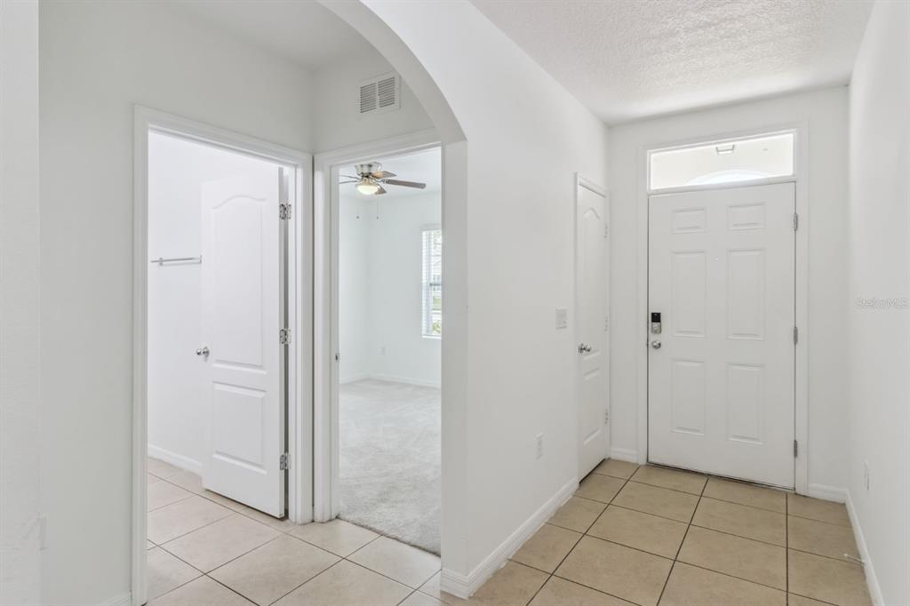 An entryway with tiled floors, an arched doorway, and a view into a carpeted bedroom — 4257 ROBERTA DRIVE, WINTER HAVEN, FL