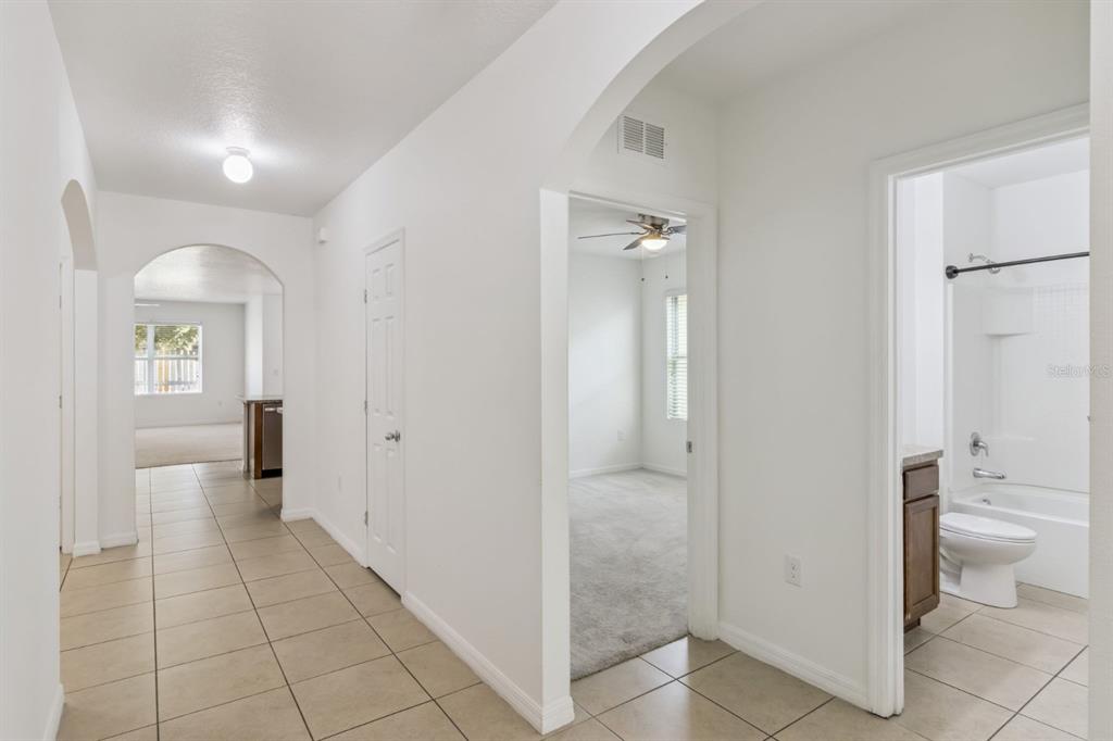 A hallway with tile flooring leads to a bedroom and a bathroom with a tub — 4257 ROBERTA DRIVE, WINTER HAVEN, FL