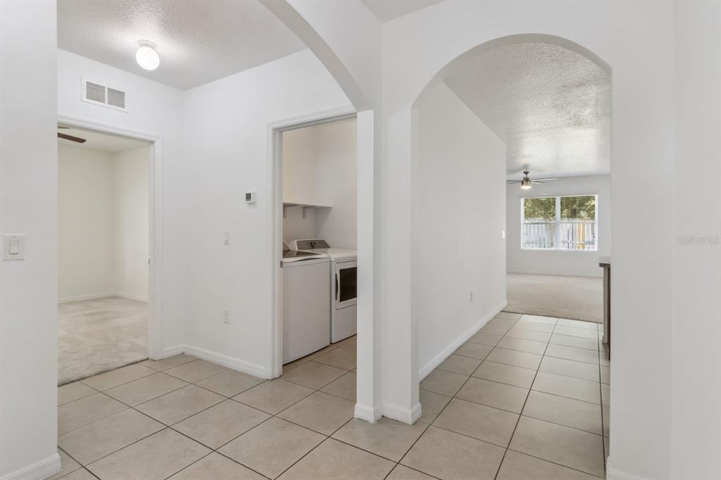 A tiled hallway leads to a laundry room and an arched opening to a living area — 4257 ROBERTA DRIVE, WINTER HAVEN, FL