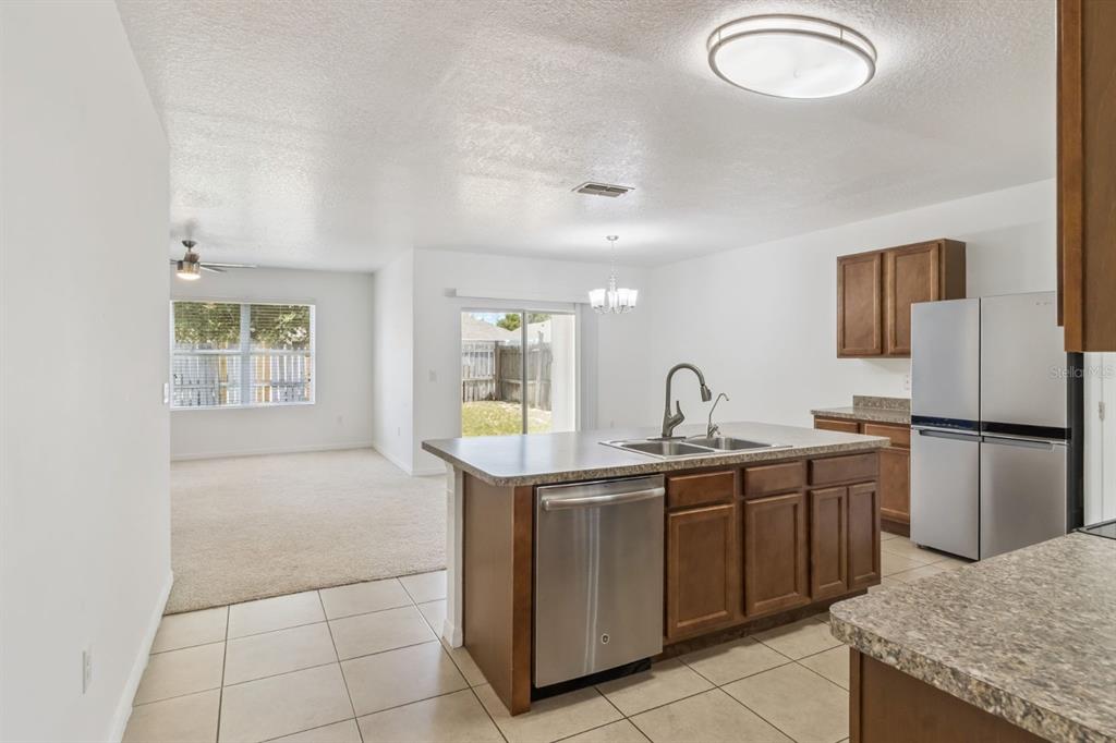 A kitchen with a center island and stainless steel appliances overlooks an open living area — 4257 ROBERTA DRIVE, WINTER HAVEN, FL