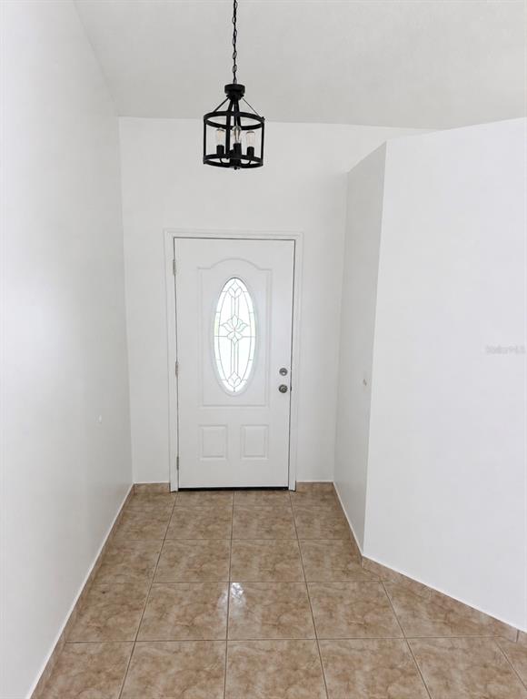 An entryway features a white front door with a decorative glass insert and tile flooring — 1901 ASHLEY OAKS COURT, ST CLOUD, FL