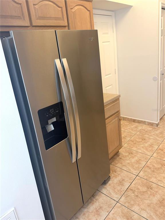 A stainless steel side-by-side refrigerator stands in a kitchen with light wood cabinets and tile flooring — 1901 ASHLEY OAKS COURT, ST CLOUD, FL
