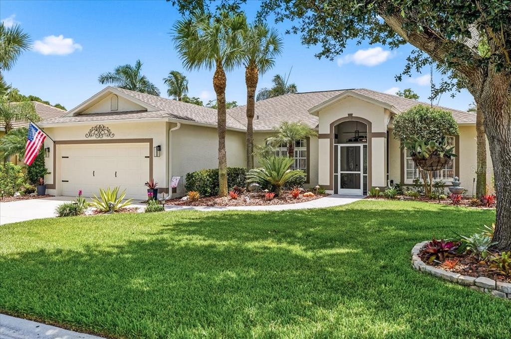 A single-story suburban house with a two-car garage, palm trees, and a landscaped front yard — 8905 CYPRESS PRESERVE PLACE, FORT MYERS, FL