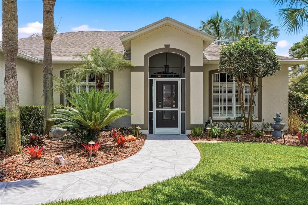 A front view of a single-story house with a stone walkway leading to the entrance — 8905 CYPRESS PRESERVE PLACE, FORT MYERS, FL
