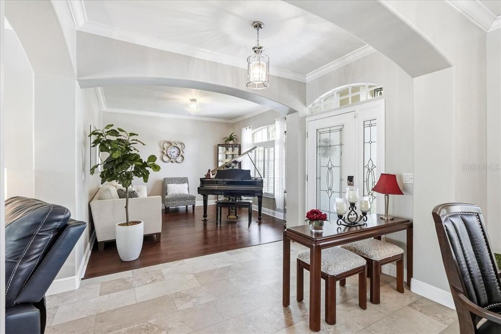 A foyer with tile flooring leads into a living area featuring a grand piano — 8905 CYPRESS PRESERVE PLACE, FORT MYERS, FL