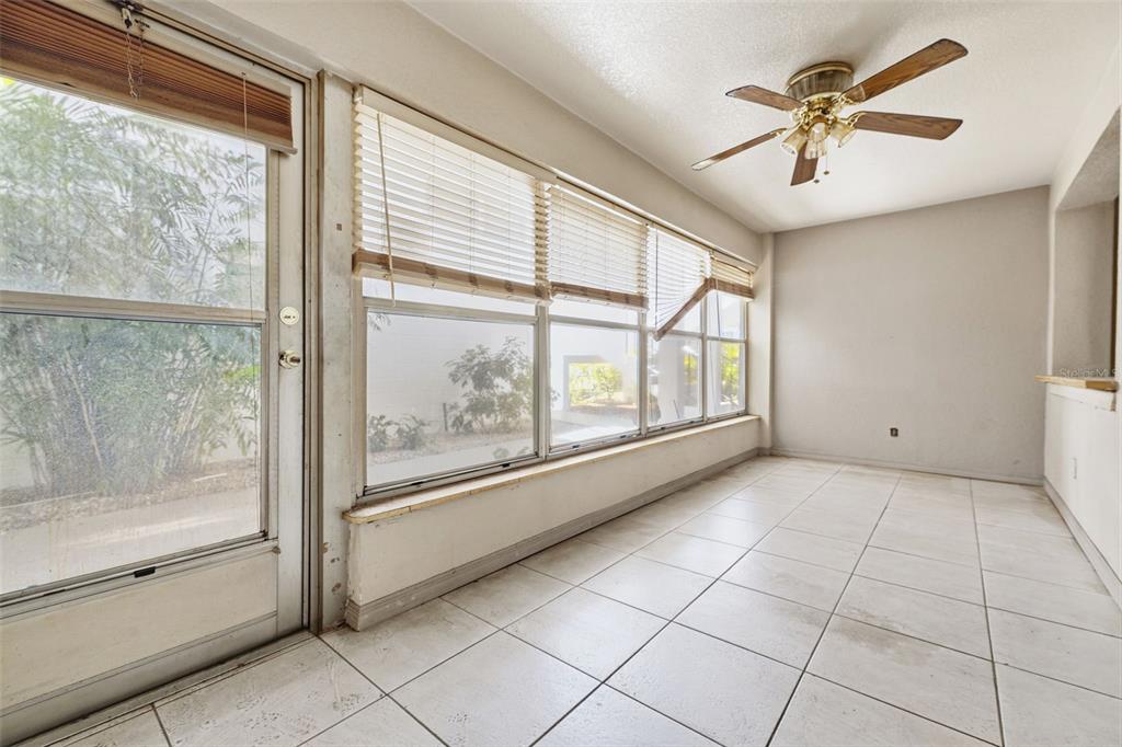 A sunroom with white tile floors, a ceiling fan, and large windows with blinds — 3100 HARTFORD STREET N UNIT 129, ST PETERSBURG, FL