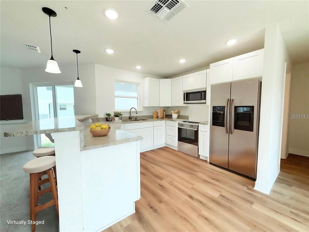 A kitchen with white cabinets, stainless steel appliances, and a granite-topped island — 222 CARPENTERS WAY UNIT 66, LAKELAND, FL
