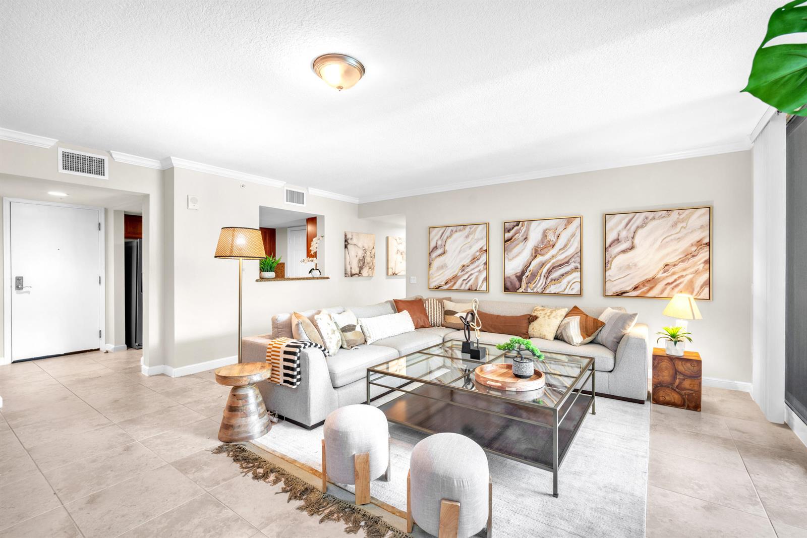 A living room features a sectional sofa, glass coffee table, and abstract wall art — 101 Plaza Real, Boca Raton FL 33432, BOCA RATON, FL
