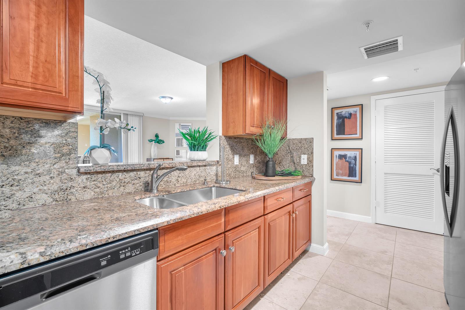 A kitchen features wood cabinets, granite countertops, a stainless steel sink, and a dishwasher — 101 Plaza Real, Boca Raton FL 33432, BOCA RATON, FL