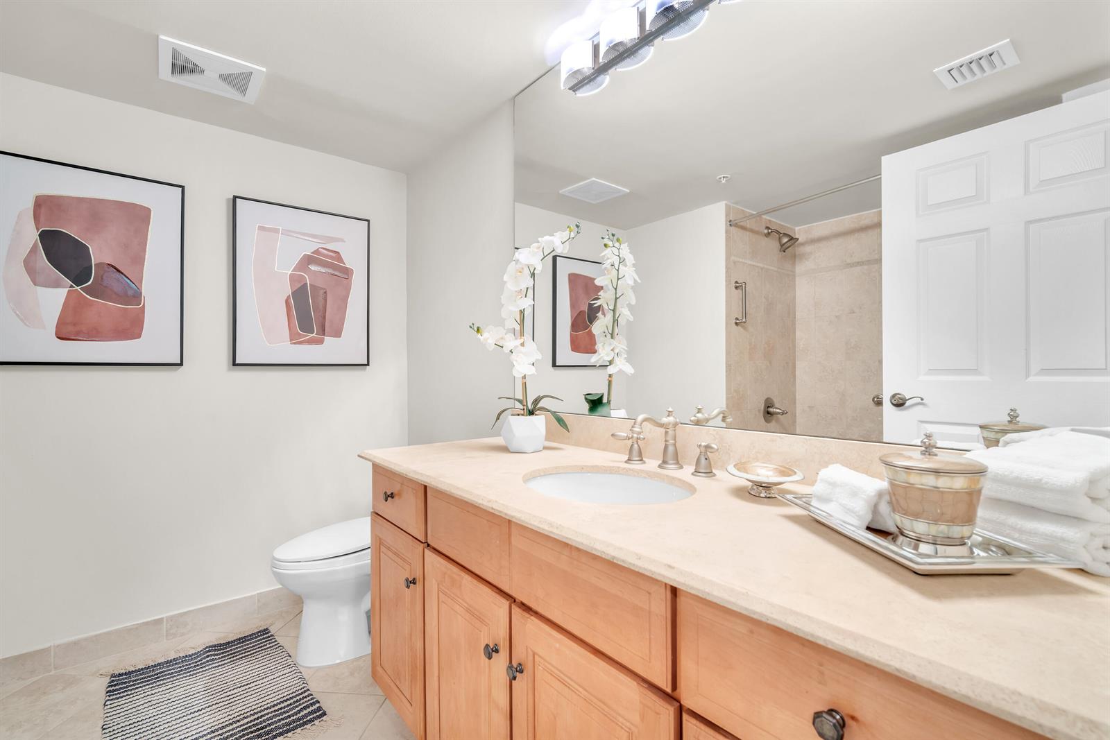 A bathroom features a wooden vanity with a stone countertop, a mirror, and a shower — 101 Plaza Real, Boca Raton FL 33432, BOCA RATON, FL