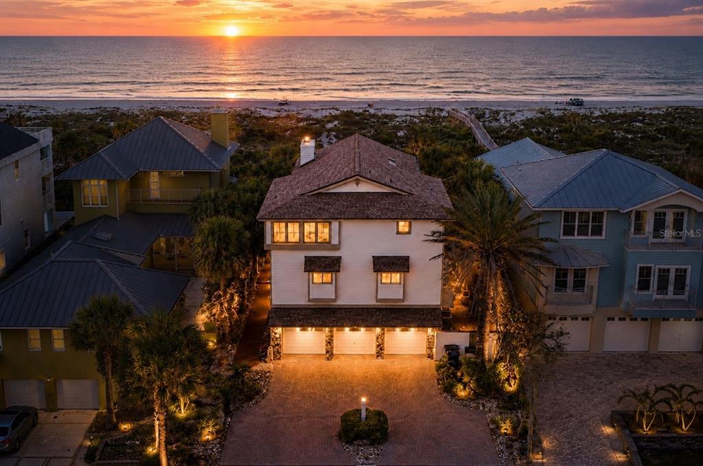 An aerial view of a three-story beachfront house with a three-car garage at sunset — 1421 N ATLANTIC AVENUE, NEW SMYRNA BEACH, FL