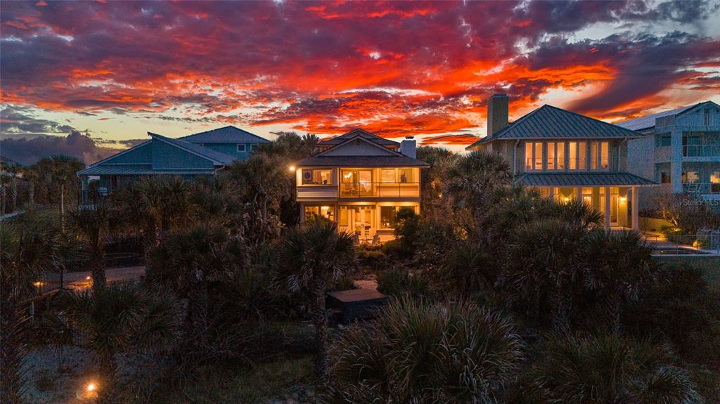 An exterior view of three coastal homes surrounded by palm trees under a vibrant sunset — 1421 N ATLANTIC AVENUE, NEW SMYRNA BEACH, FL