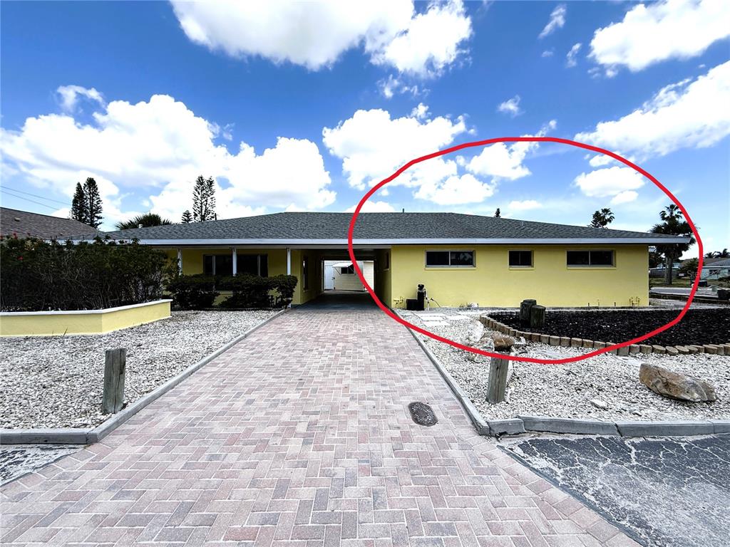 The exterior of a yellow, single-story house features a paved driveway and a carport — 500 140TH AVENUE E, MADEIRA BEACH, FL