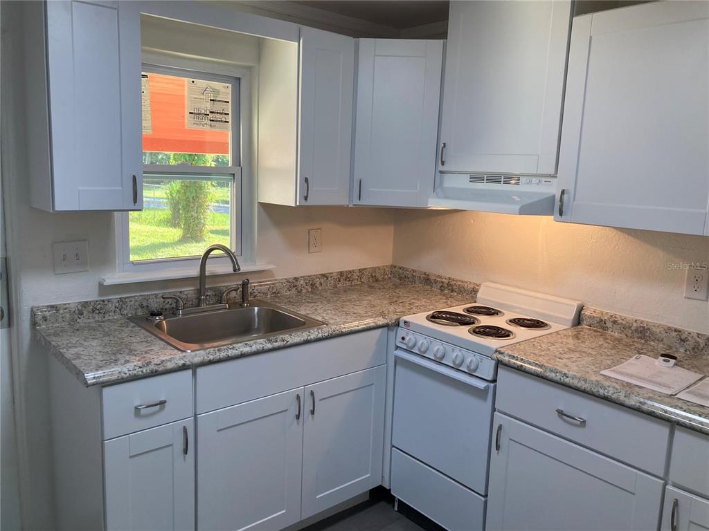 A kitchen features white cabinets, a stainless steel sink, and a white electric range — 5221 N RONALD REAGAN BOULEVARD, SANFORD, FL