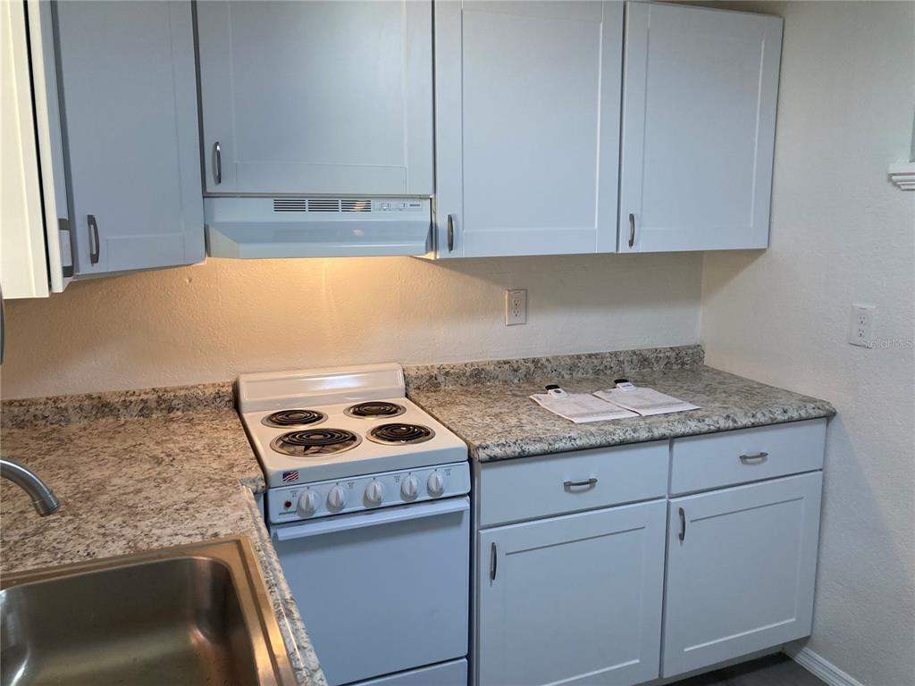 A kitchen features light gray cabinets, a white electric stove, and speckled granite countertops — 5221 N RONALD REAGAN BOULEVARD, SANFORD, FL