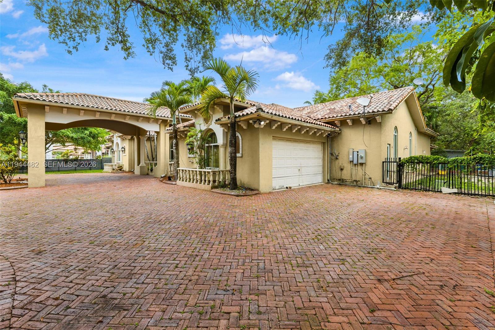 A beige house with a tiled roof, a brick driveway, and a covered porte-cochère — 7761 SW 122nd Ave, Miami FL 33183, MIAMI, FL
