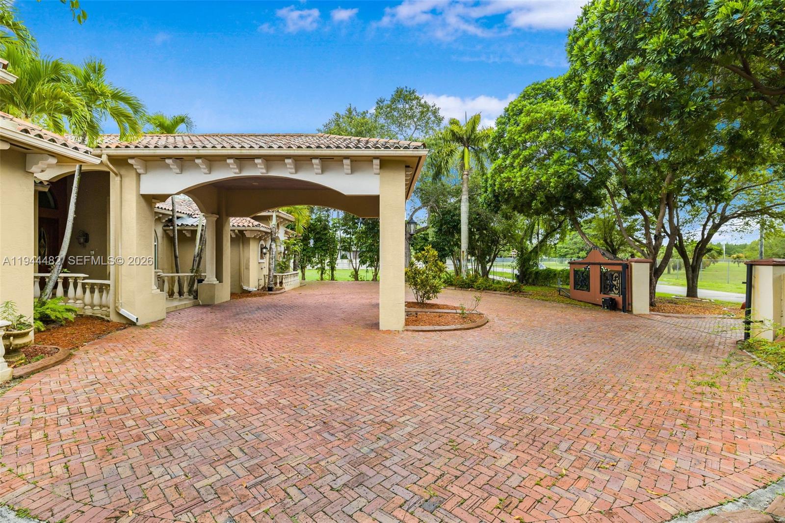 A brick driveway leads to a covered porte-cochère attached to a tan stucco house — 7761 SW 122nd Ave, Miami FL 33183, MIAMI, FL