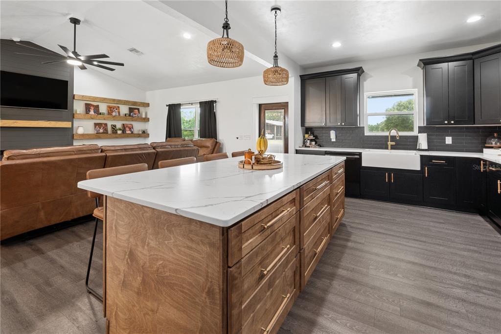 A kitchen with a wood island, white countertops, and black cabinets, open to a living area — 3396 NW 31ST AVENUE, BELL, FL