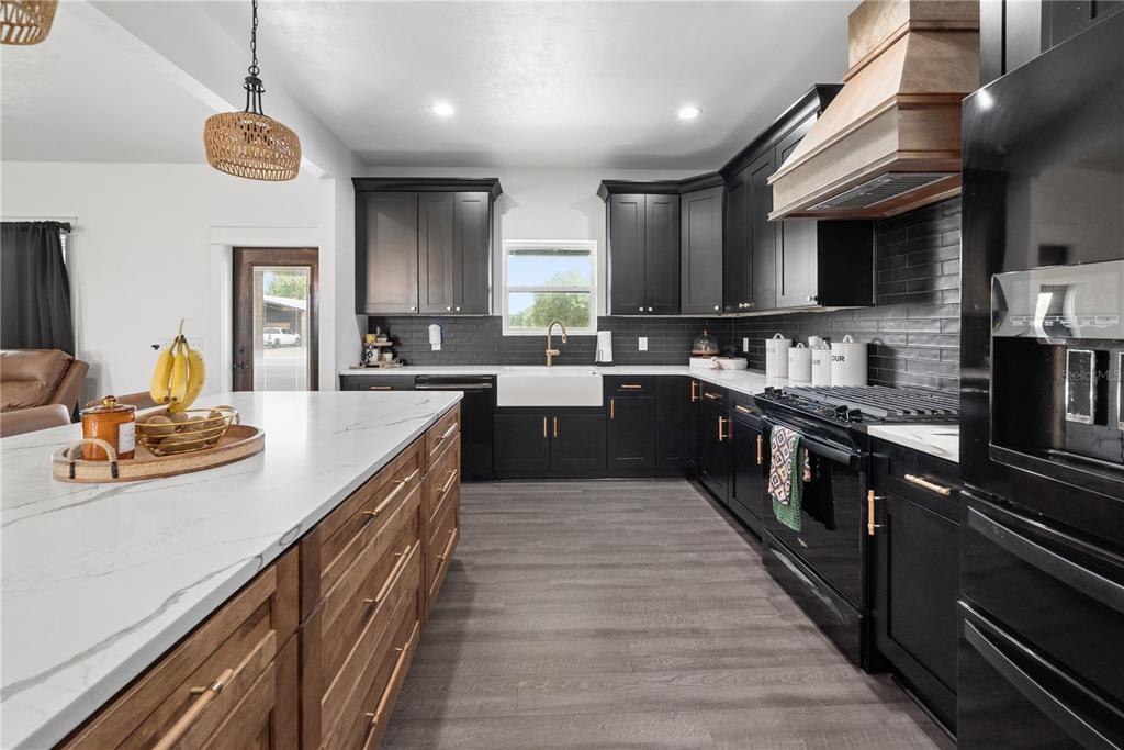 A kitchen features black cabinets, a wood-toned island with a white countertop, and dark flooring — 3396 NW 31ST AVENUE, BELL, FL