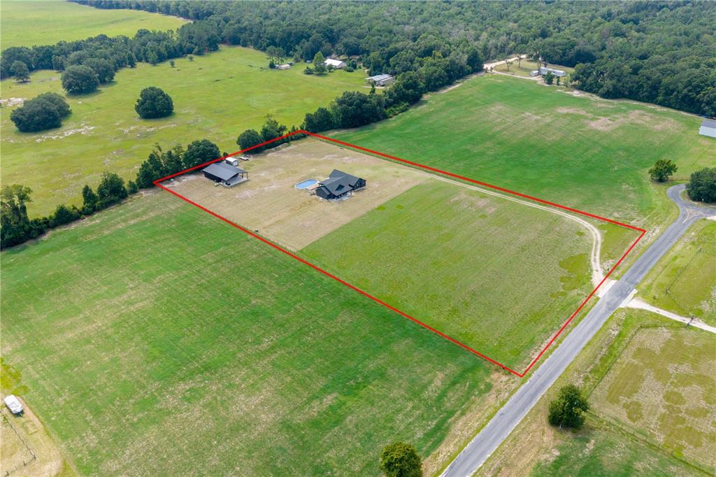 An aerial view shows a house with a pool and a detached garage on acreage — 3396 NW 31ST AVENUE, BELL, FL