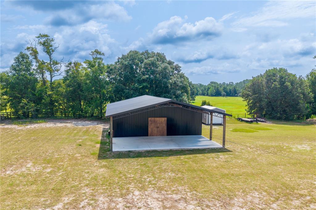 An aerial view of a dark metal barn with a concrete patio on a grassy lot — 3396 NW 31ST AVENUE, BELL, FL