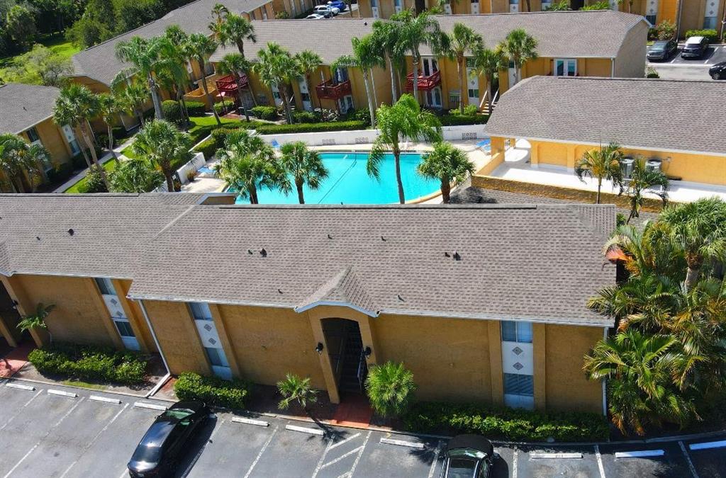 An aerial view shows a multi-story apartment complex with a central swimming pool and parking — 1841 PARAKEET WAY UNIT 1101, SARASOTA, FL
