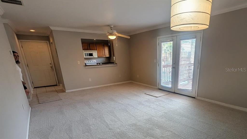 A living room with beige carpet, a ceiling fan, and a kitchen pass-through window — 1841 PARAKEET WAY UNIT 1101, SARASOTA, FL