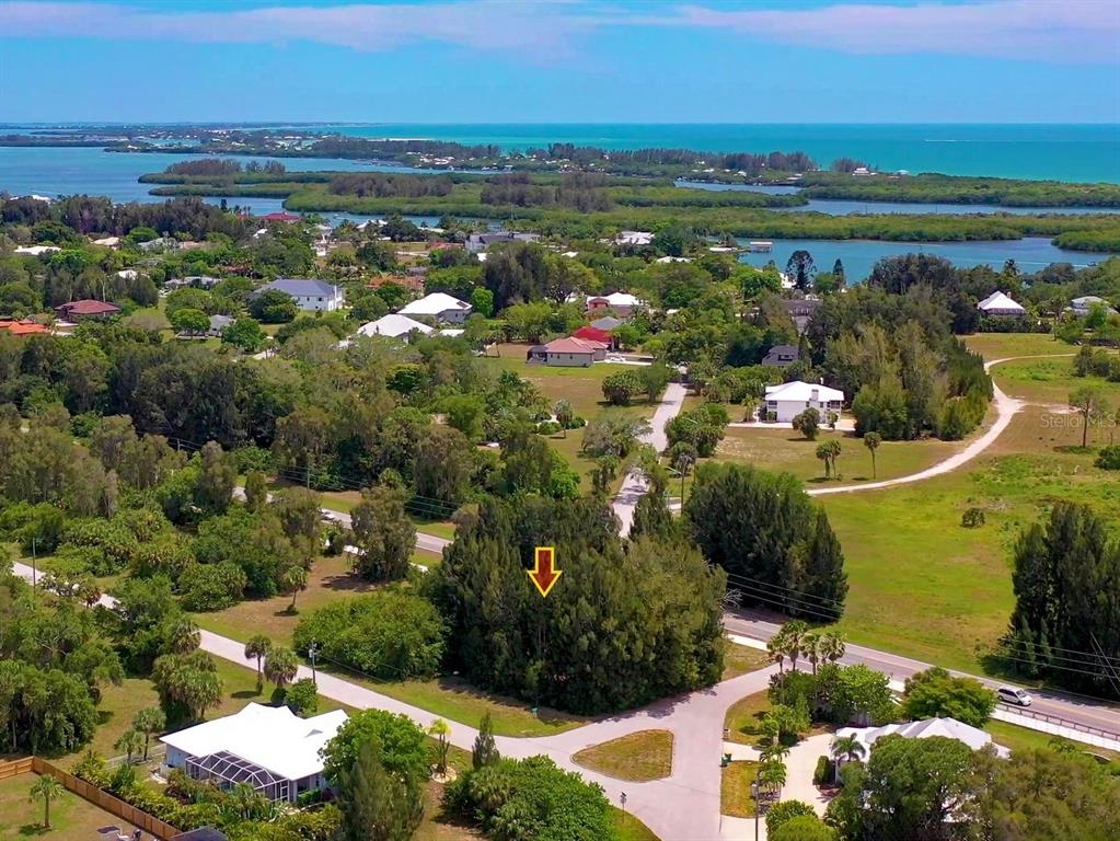An aerial view shows a wooded lot marked by an arrow in a coastal neighborhood — 41 BONITA STREET, PLACIDA, FL