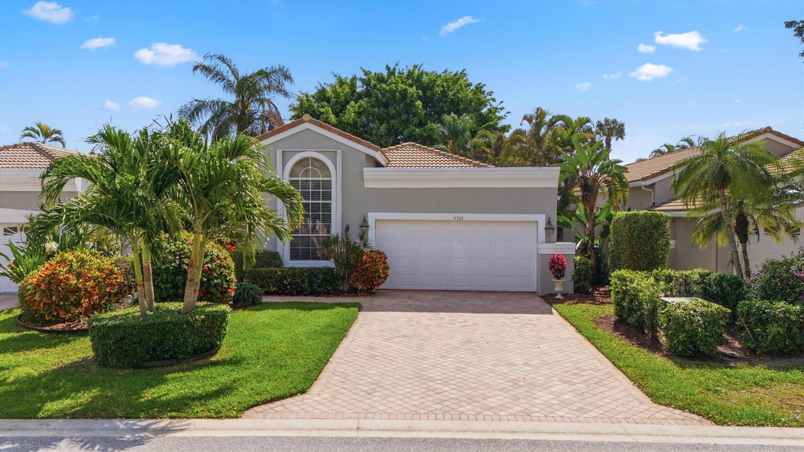 A single-story house with a white garage, arched window, and paved driveway under a blue sky — 4730 Carlton Golf Drive, Lake Worth FL 33449, LAKE WORTH, FL
