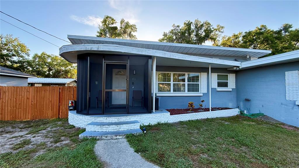 A single-story house with a blue exterior, a screened-in front porch, and a wooden fence — 811 22ND STREET NW, WINTER HAVEN, FL