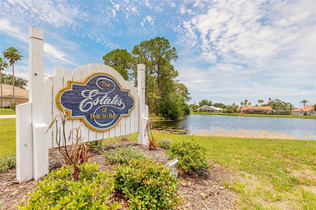 A sign for The Estates of Pelican Bay stands beside a lake and houses — 121 KING EIDER COURT, DAYTONA BEACH, FL