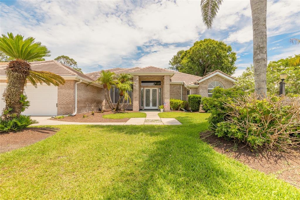 A single-story brick house with a tiled roof, front lawn, and palm trees — 121 KING EIDER COURT, DAYTONA BEACH, FL